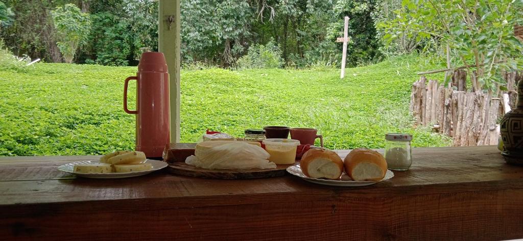 ein Tisch mit Brot und ein Teller mit Essen drauf. in der Unterkunft Canastra Hostel e Camping - quartos in Vargem Bonita