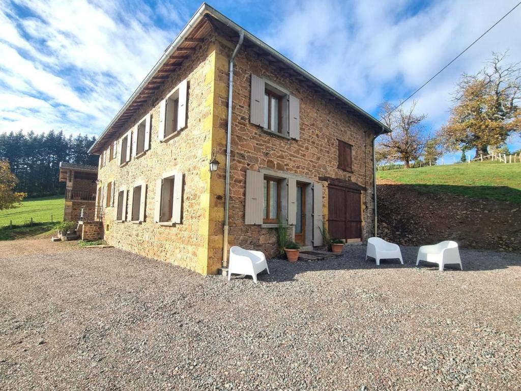 a brick building with white chairs in front of it at Charmant Gîte Cocooning avec Terrasse et Animaux Acceptés - FR-1-496-306 in Belmont-de-la-Loire