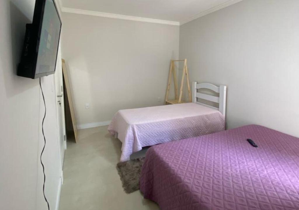 Kleines Zimmer mit 2 Betten und einem TV in der Unterkunft Suíte Premium in Itajaí