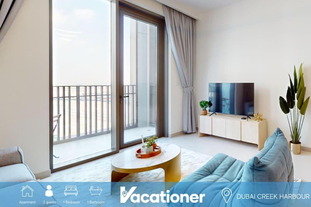 Summer at Creek Beach - Vacationer في دبي: غرفة معيشة مع أريكة زرقاء وتلفزيون