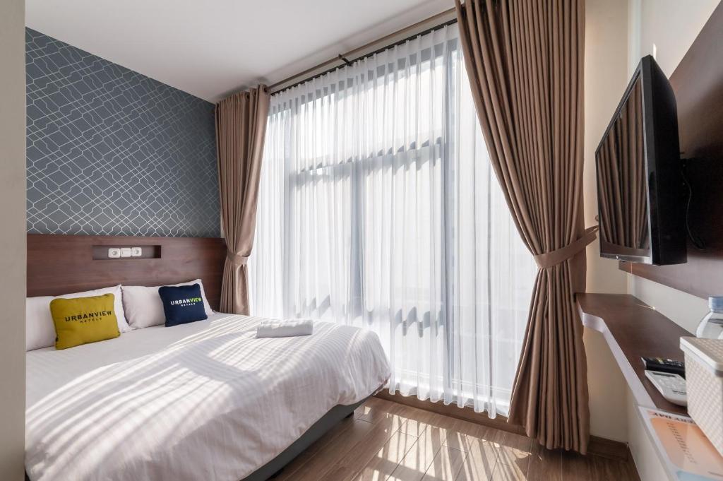 um quarto com uma cama e uma grande janela em Urbanview Hotel Cengkareng Jakarta by RedDoorz em Jacarta