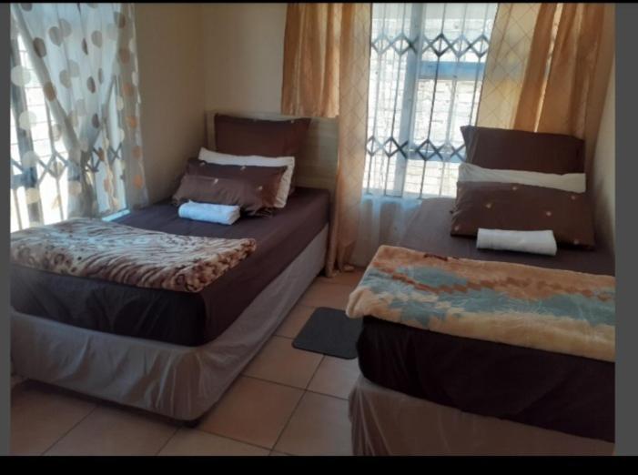 a bedroom with two beds and a window at Rona Thina House in Pimville