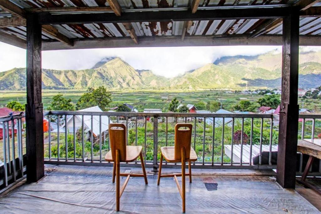two chairs on a balcony with a view of mountains at Villa Strawberry Sembalun in Sembalunbumbung