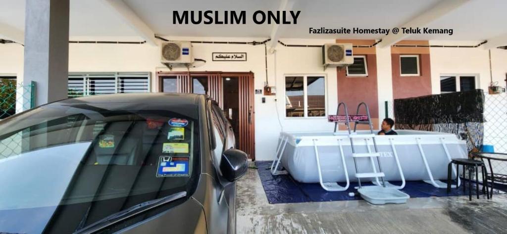 une voiture garée à côté d'une baignoire en face d'une maison dans l'établissement Fazlizasuite Homestay @ Teluk Kemang-Muslim Preferred, à Port Dickson