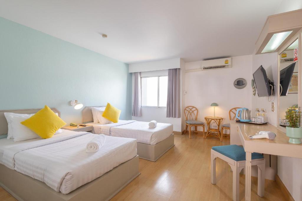 a hotel room with two beds and a living room at Green Palace Hotel in Chiang Mai