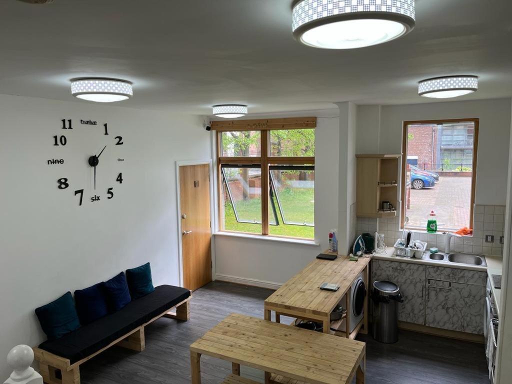 a living room with a table and a clock on the wall at City Centre 4 in Manchester