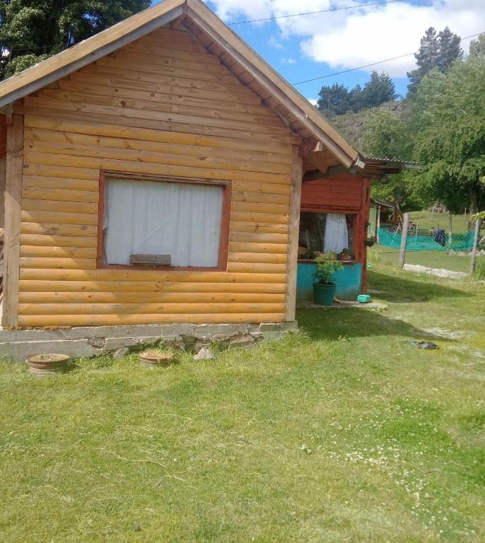 uma cabana de madeira com uma janela num quintal em Casa estilo cabaña em El Bolsón