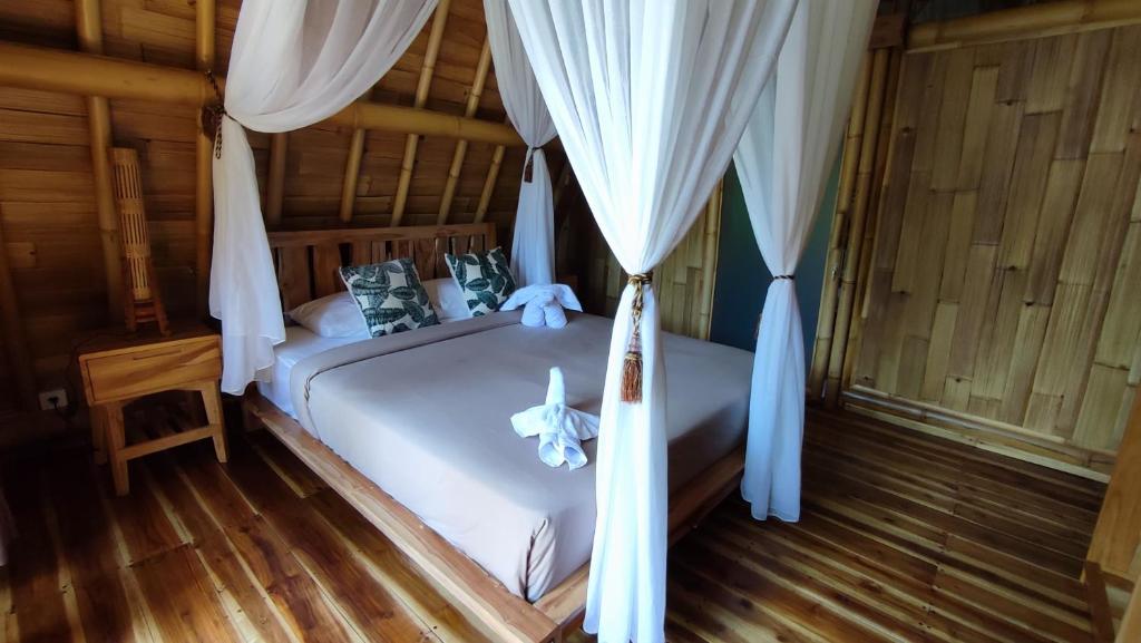 a bedroom with a white bed with curtains and wooden floors at Sekumpul Bali Hidden Space in Singaraja