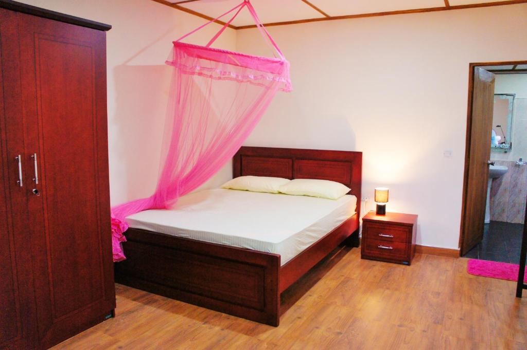 a bedroom with a bed with a pink mosquito net at Nylander Co-operative Society in Mahabage