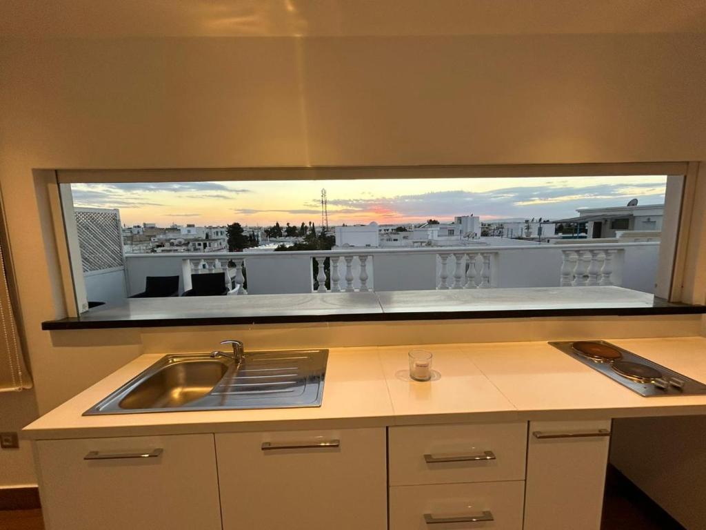 a kitchen with a large window over a kitchen sink at Duplex avec Rooftop a la Marsa in La Marsa