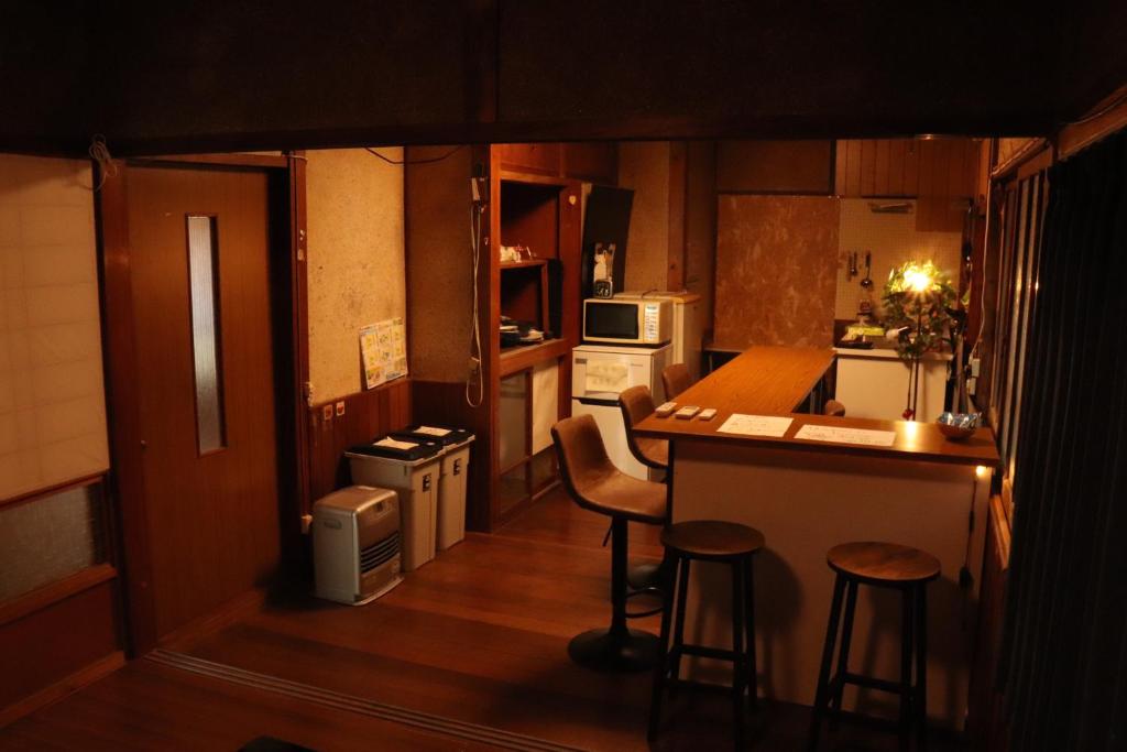 eine kleine Küche mit einer Theke und Hockern in der Unterkunft 【一棟貸し切り】海辺の静かな古民家宿『１』 in Tateishi