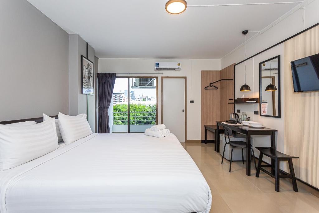 a bedroom with a large white bed and a desk at Infinite Hotel-Ratchada in Bangkok