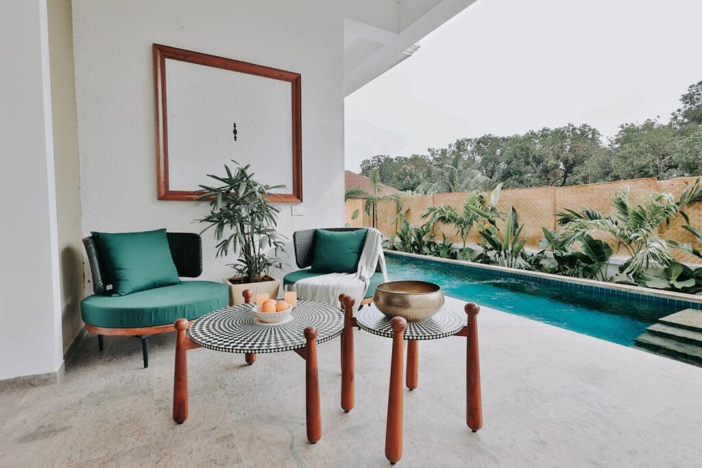 uma sala de estar com duas cadeiras e uma mesa e uma piscina em Eclectic Luxury 3bhk Villa with Private Pool em Mapuçá
