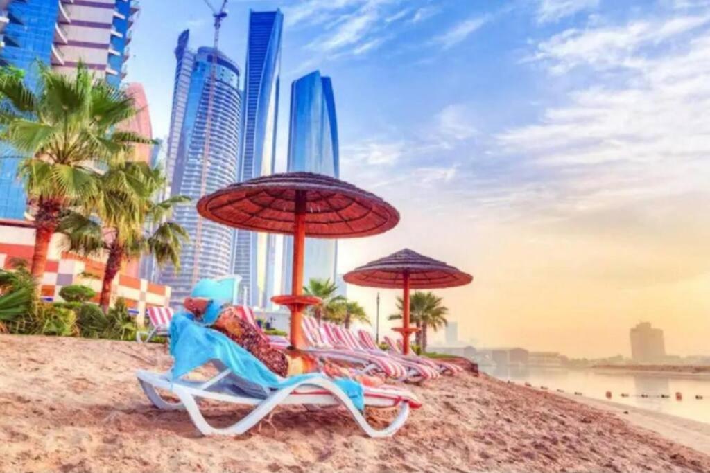 een groep strandstoelen en parasols op een strand bij Karen's Studio in corniche Abu Dhabi behind Shikha Fatima park in Abu Dhabi