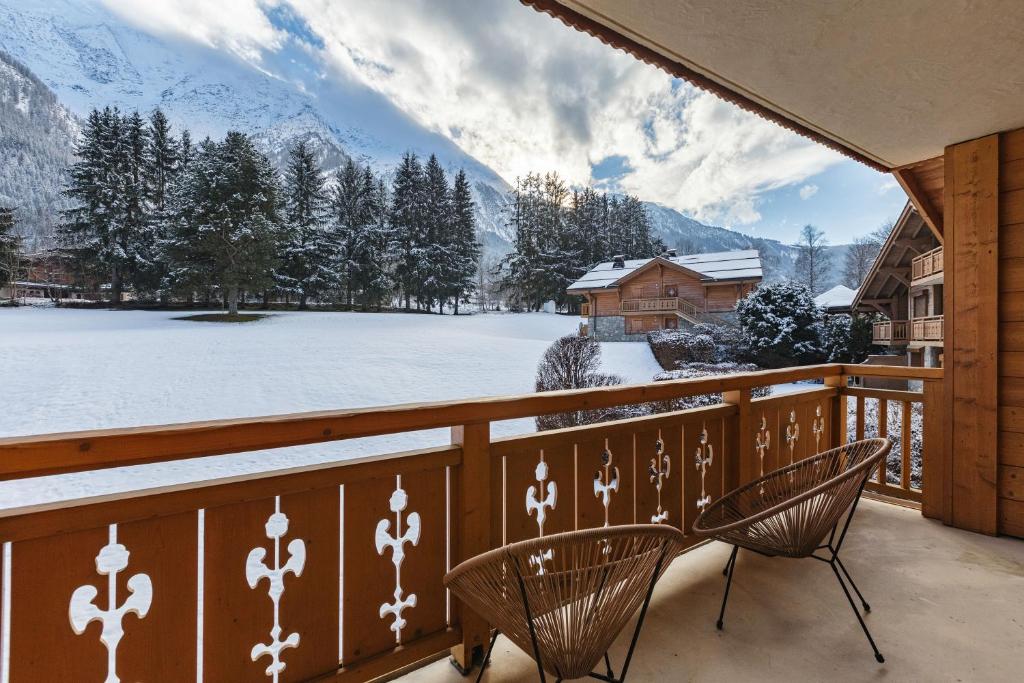 uma varanda com duas cadeiras e montanhas cobertas de neve em Cottage des Houches - Happy Rentals em Les Houches