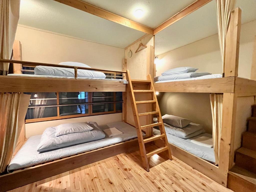 a bunk bed room with three bunk beds and a ladder at おとまち 甘藍 Otomachi Kanran in Kure