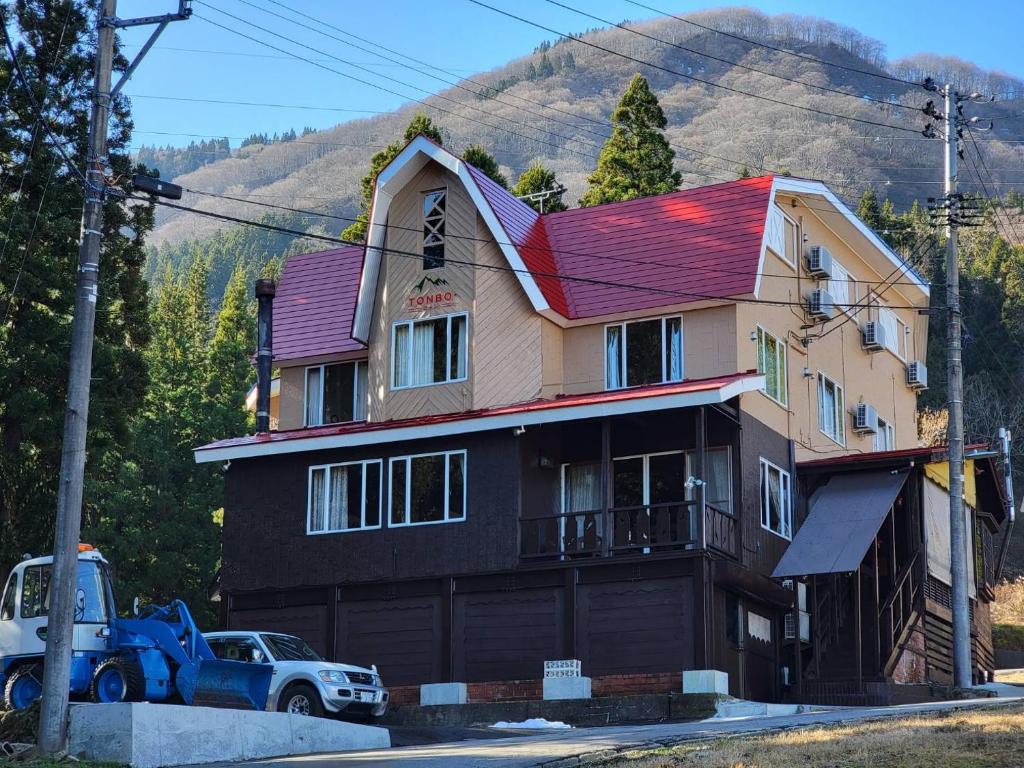 une maison avec un toit rouge et un camion garé devant dans l'établissement ロッジＴＯＮＢＯ・石打, à Minami Uonuma