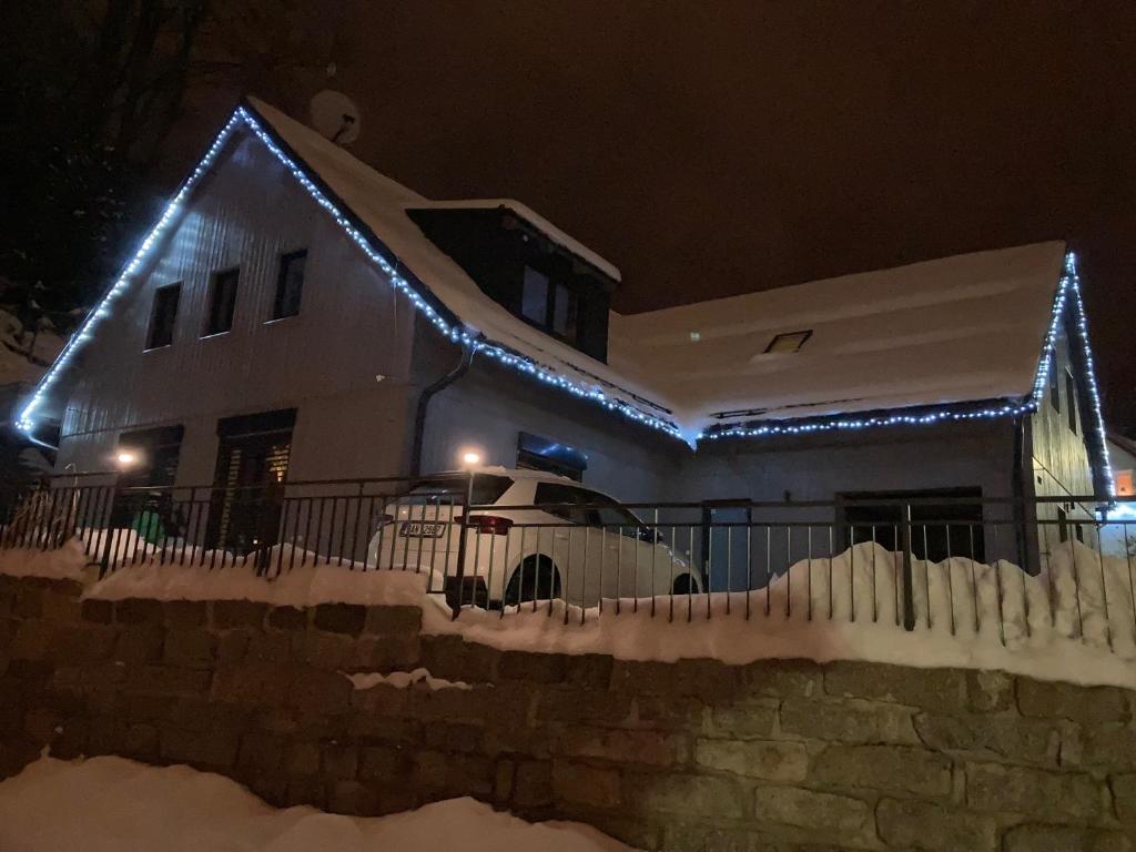 a house with christmas lights on it in the snow at Apartmány U tří bratrů in Bedřichov