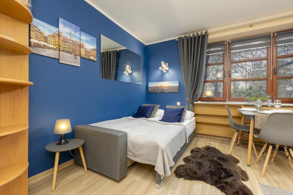 a blue bedroom with a bed and a table at Rent like home - Comfortable Studio Sapiezynska in Warsaw
