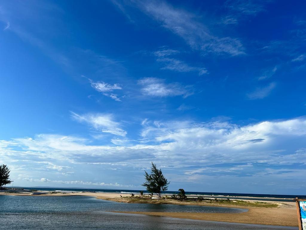 un cuerpo de agua bajo un cielo azul con nubes en Barra house, en Inhambane