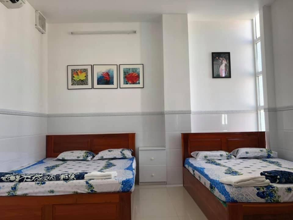 a bedroom with two beds and two windows at Nhà nghỉ Vân Anh in Ấp Rạch Mẹo