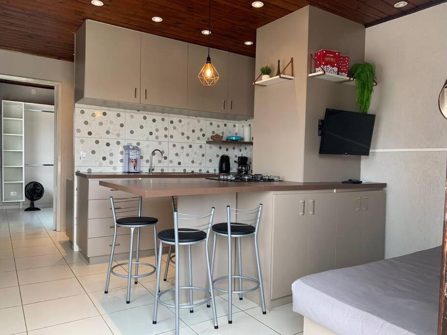 a kitchen with a counter and stools in it at Studio Residencial Curitiba Apartament in Curitiba