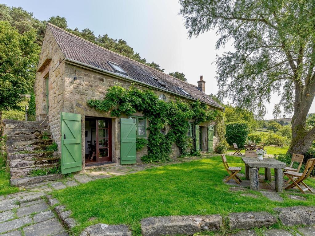 an old stone house with green doors and a table at 3 Bed in Gratton 78618 in Youlgreave