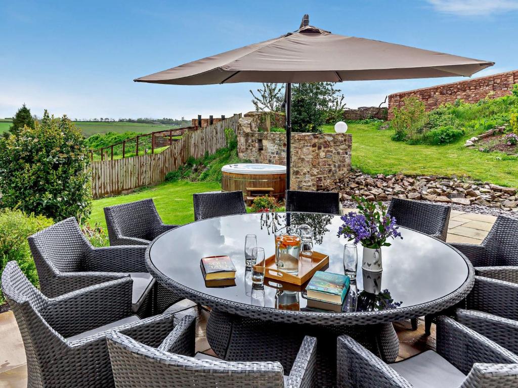 a table and chairs with an umbrella on a patio at 5 Bed in Ashbrittle 77900 