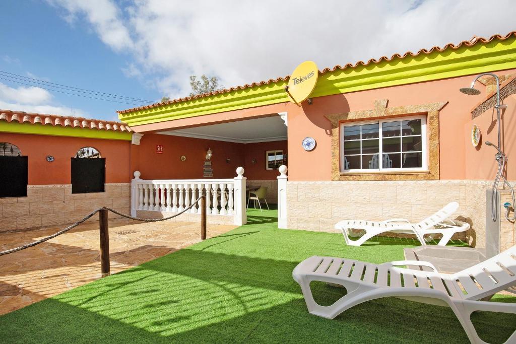 una casa con un patio verde con dos bancos blancos en Casa Doña Margarita, en Tuineje