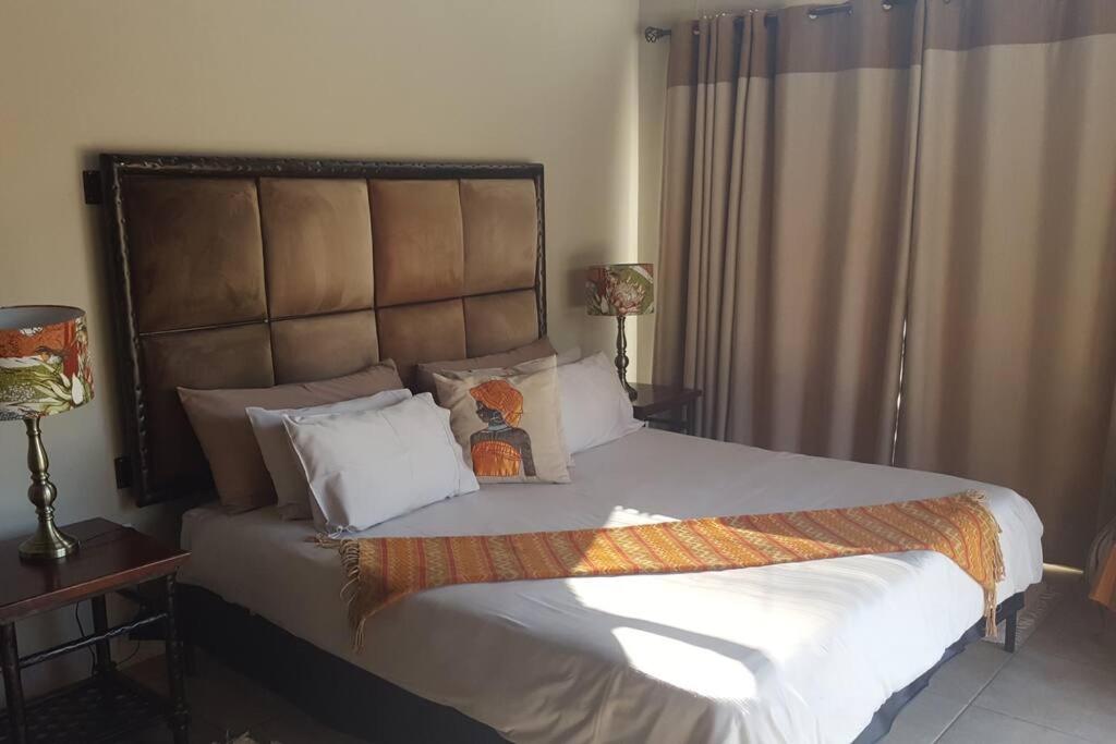 um quarto com uma cama grande com lençóis brancos e almofadas em Zebula Golf Estate and Spa - Impala Valley Pax 8 - Moi Signature Luxury villa em Mabula