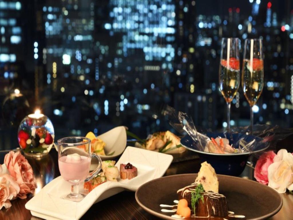 a table with plates of food and glasses of wine at Shinjuku Prince Hotel in Tokyo