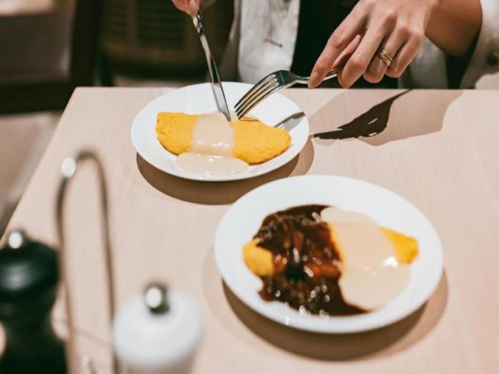 a person is eating food on two plates on a table at Shinjuku Prince Hotel in Tokyo