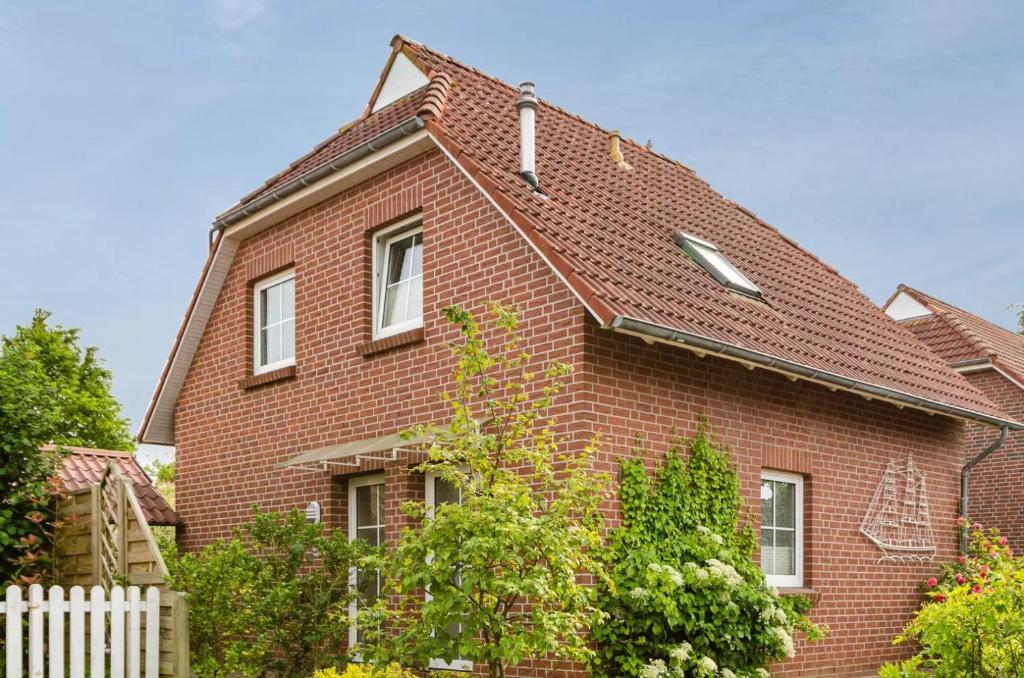una casa in mattoni rossi con tetto di Hübsche OG-Wohnung für mx. 3 Personen im Herzen von Neßmersiel a Nessmersiel