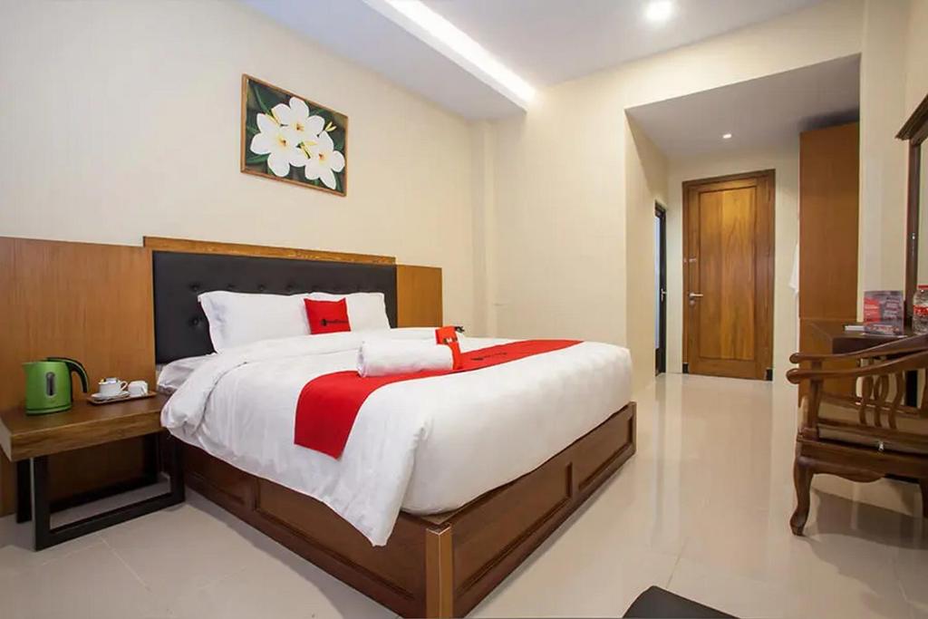 een slaapkamer met een groot bed met een houten hoofdeinde bij RedDoorz Premium @ Jalan Cengkeh Malang in Malang
