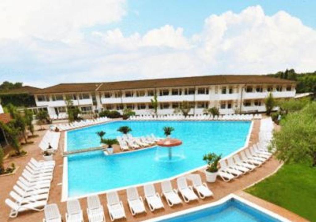 a large swimming pool with white chairs and a building at Hotel Centro Turistico Gardesano in Bussolengo