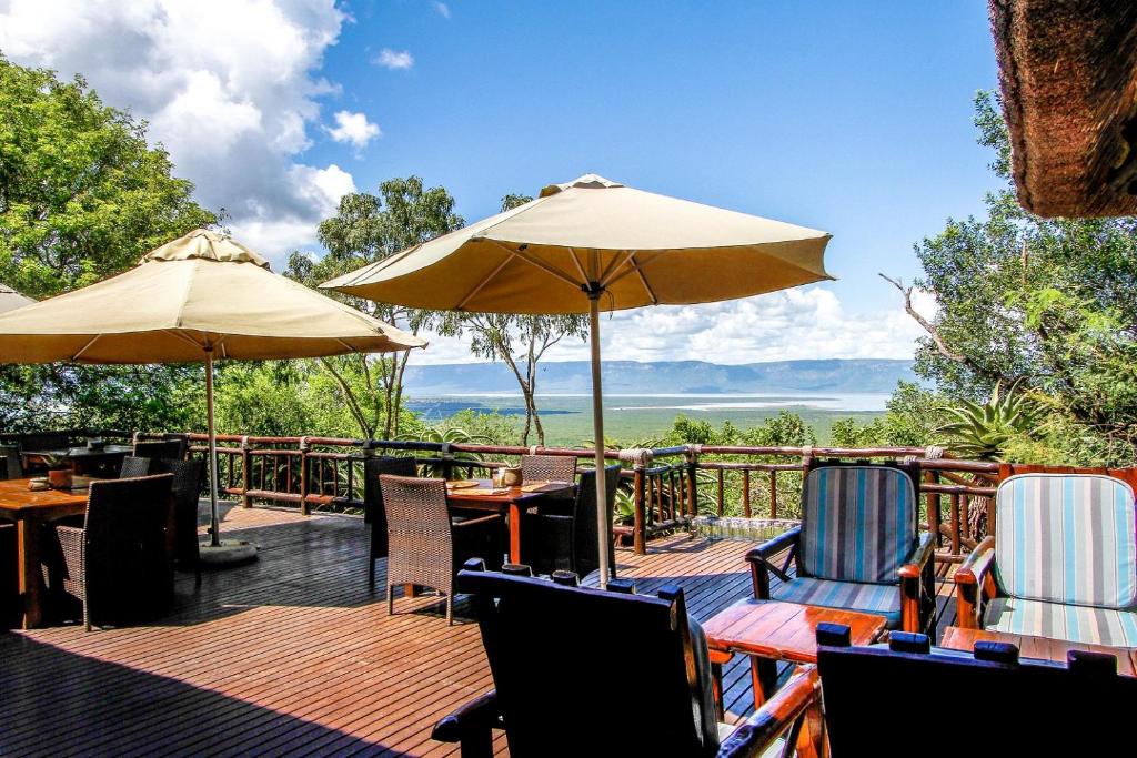 a deck with tables and chairs and umbrellas at Shayamoya Tiger Fishing and Game Lodge in Pongola Game Reserve