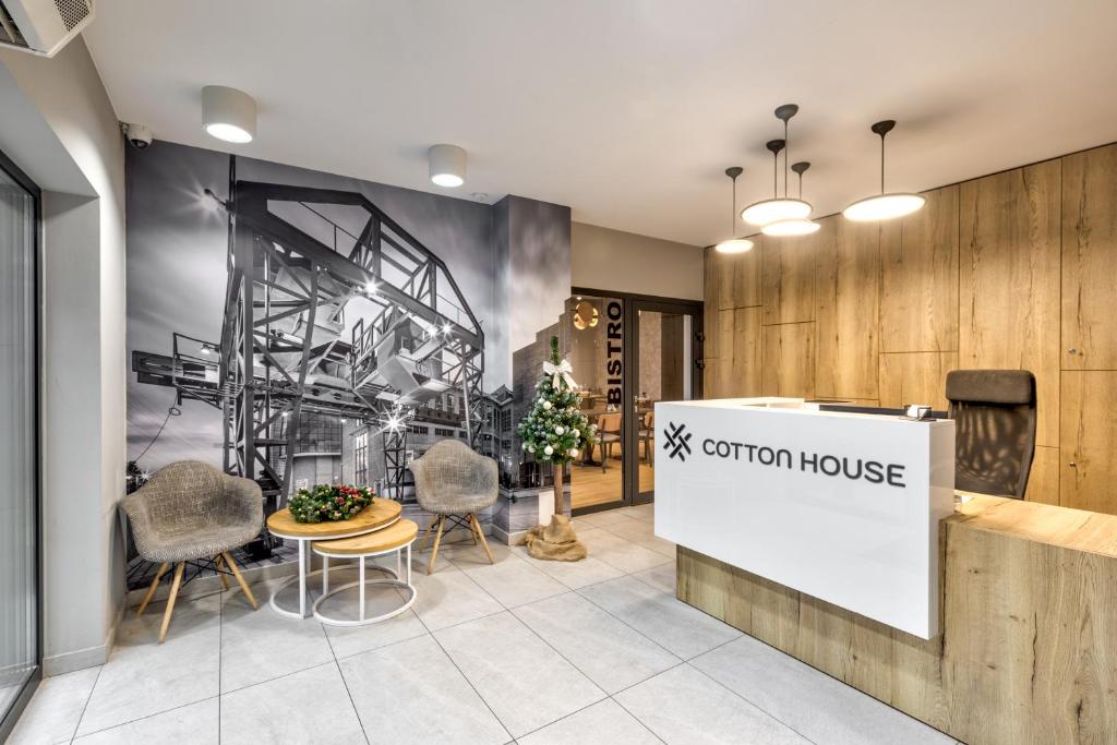 a lobby with a convention house sign and chairs at Cotton House in Łódź