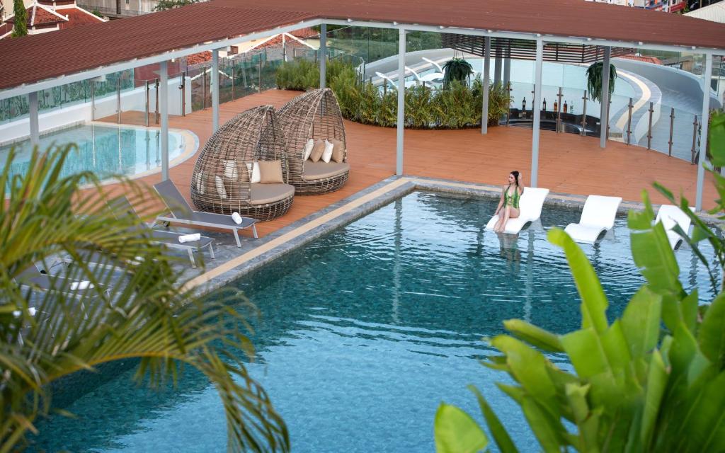 uma piscina com espreguiçadeiras e uma mulher na água em Koulen Central Hotel em Siem Reap