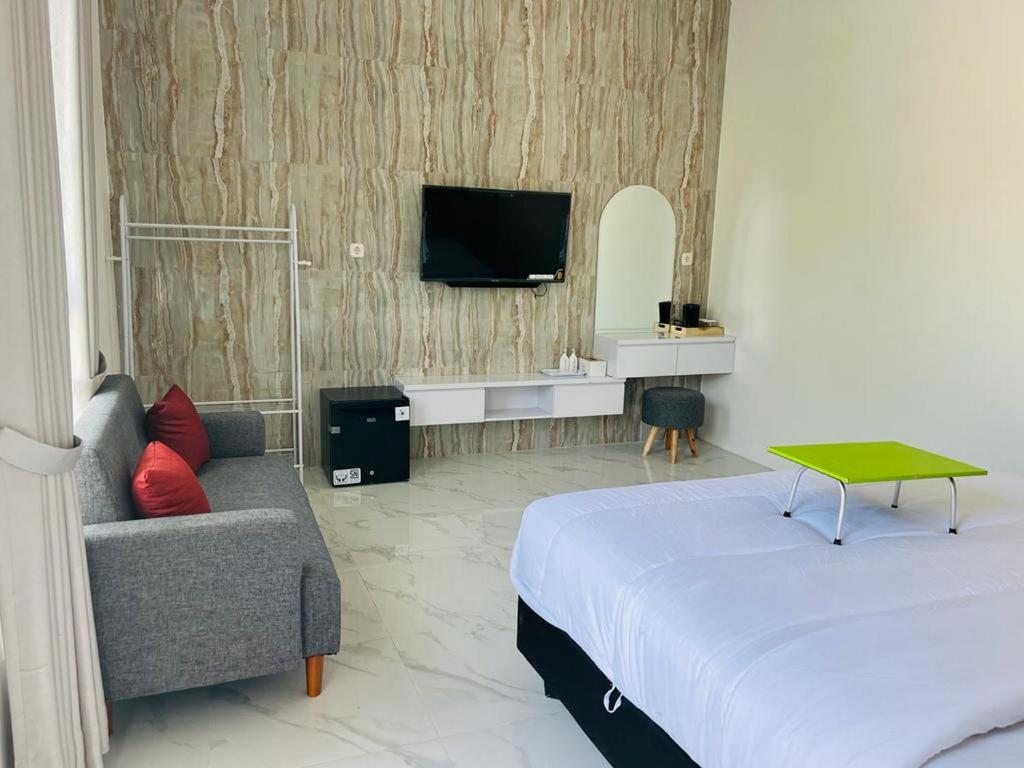 una camera con letto, divano e TV di Urbanview Hotel Nimara Ngawi by RedDoorz a Ngawi
