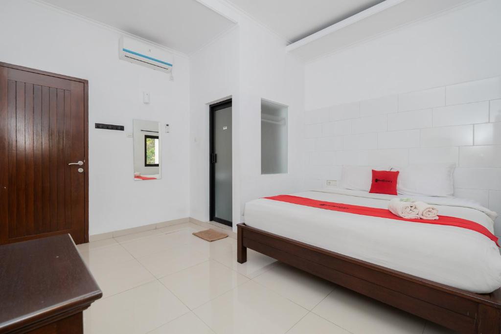 a bedroom with a bed in a white room at RedDoorz near Jawa Timur Park 3 in Karangploso