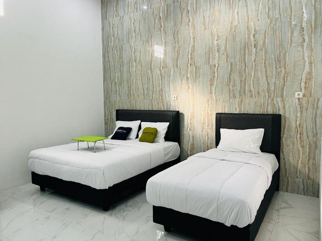 2 letti posti uno accanto all'altro in una stanza di Urbanview Hotel Nimara Ngawi by RedDoorz a Ngawi