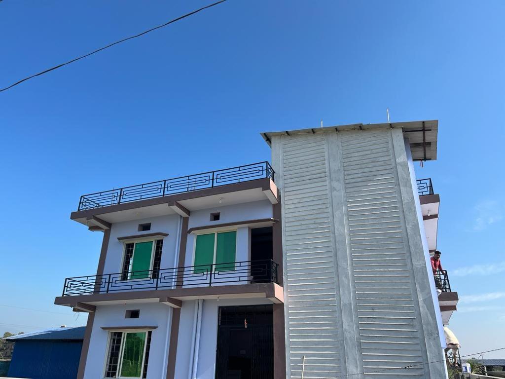 a white building with a balcony on the side of it at Pokhari Cottage Private Limited in Bahāsi