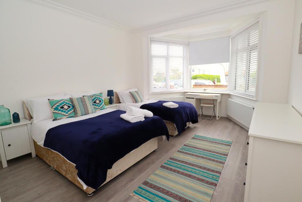 a bedroom with a bed and a desk and windows at Eastbourne Beautiful Seafront house in Eastbourne