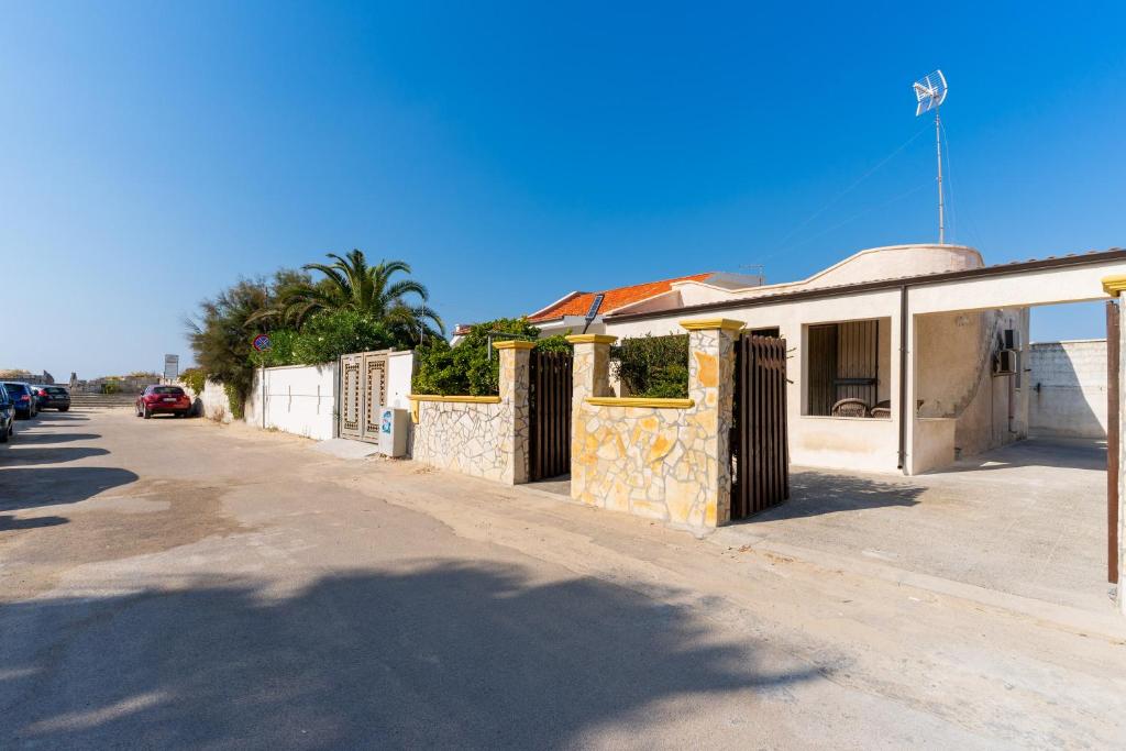 un bâtiment avec une clôture sur le côté d'une rue dans l'établissement Villa letizia Baia del sol, à Porto Cesareo