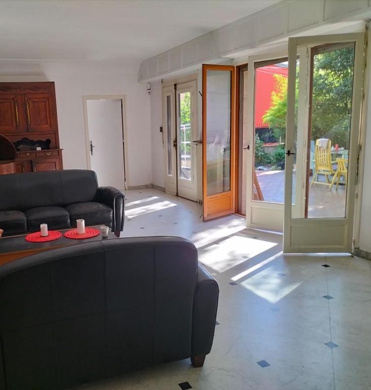 un salon avec un canapé et des portes coulissantes en verre dans l'établissement Magnifique maison + jardin à Paris Porte des Lilas, à Bagnolet