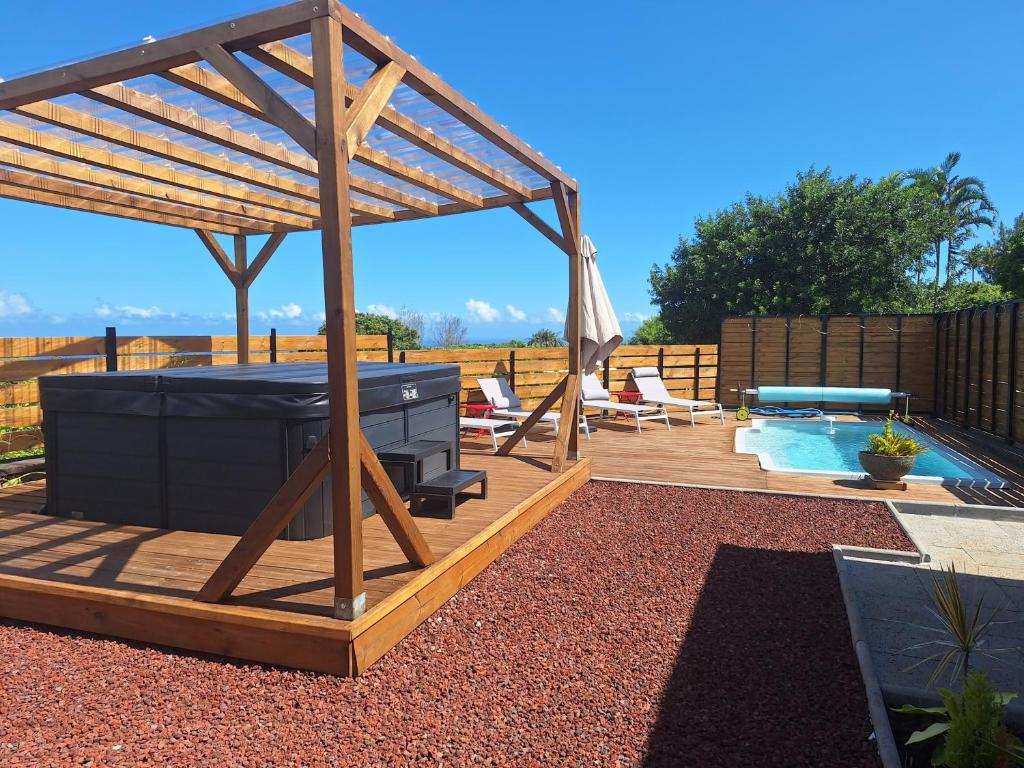 a wooden gazebo with a pool in a yard at Le Cyprès, billard piscine et jacuzzi, classé 4 étoiles in Saint-Joseph