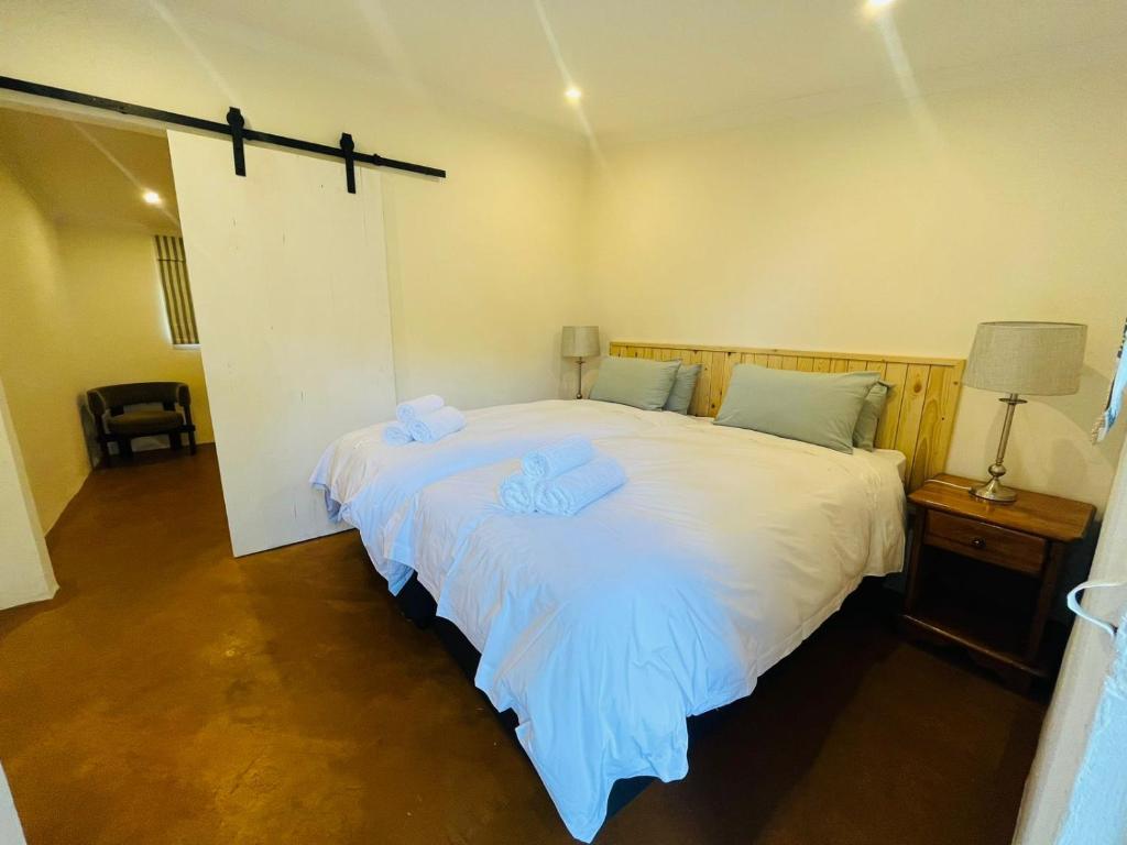a bedroom with a large white bed with two towels on it at Hebron Haven Hotel in Dargle