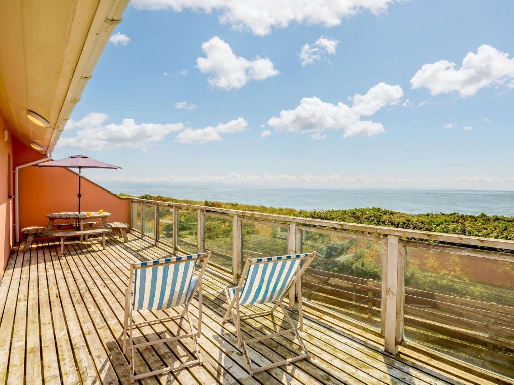 a balcony with two chairs and a table and the ocean at 3 Bed in Pwllheli 89023 in Pwllheli