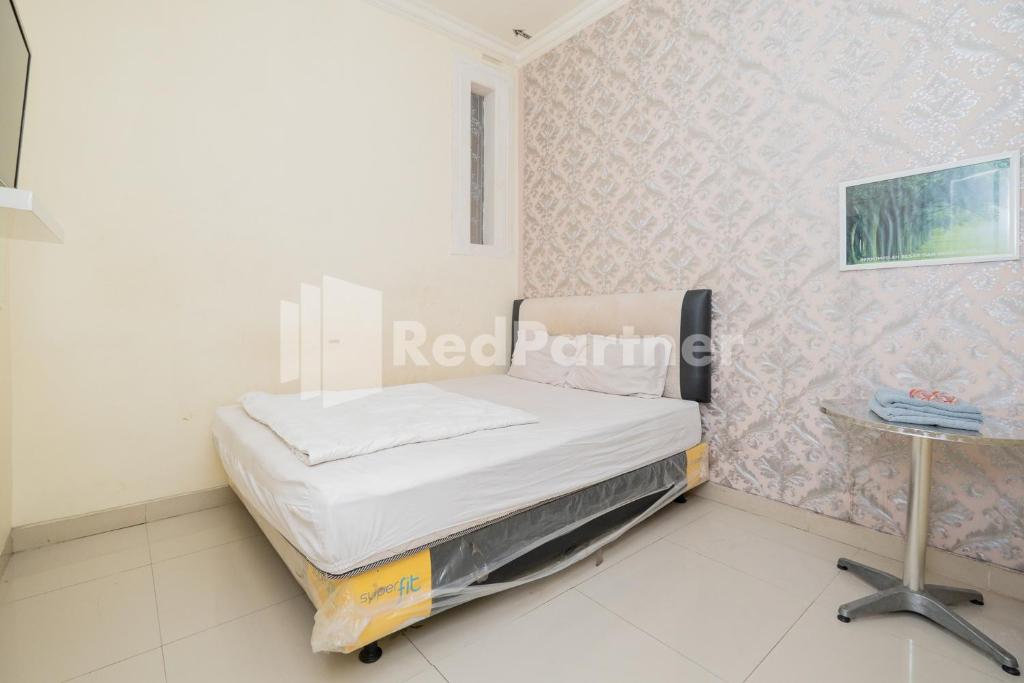 ein Krankenhauszimmer mit einem Bett und einem Tisch in der Unterkunft Omah Bratan at Sawojajar Mitra RedDoorz in Ngadipuro