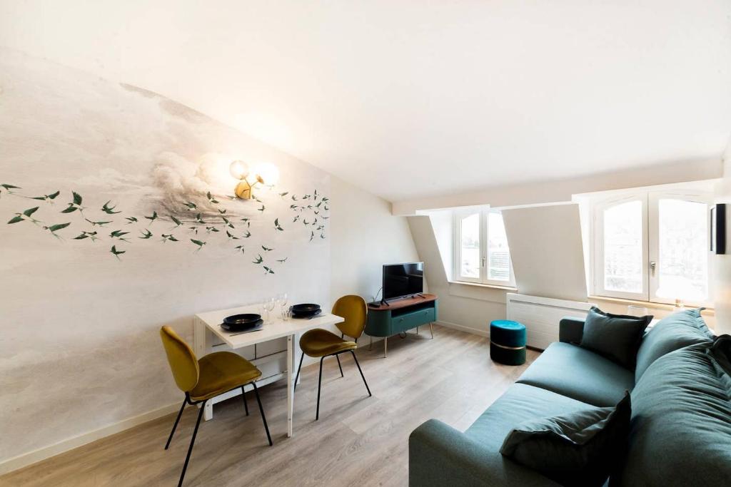 a living room with a couch and a table with chairs at Nid douillet avec vue in Lyon
